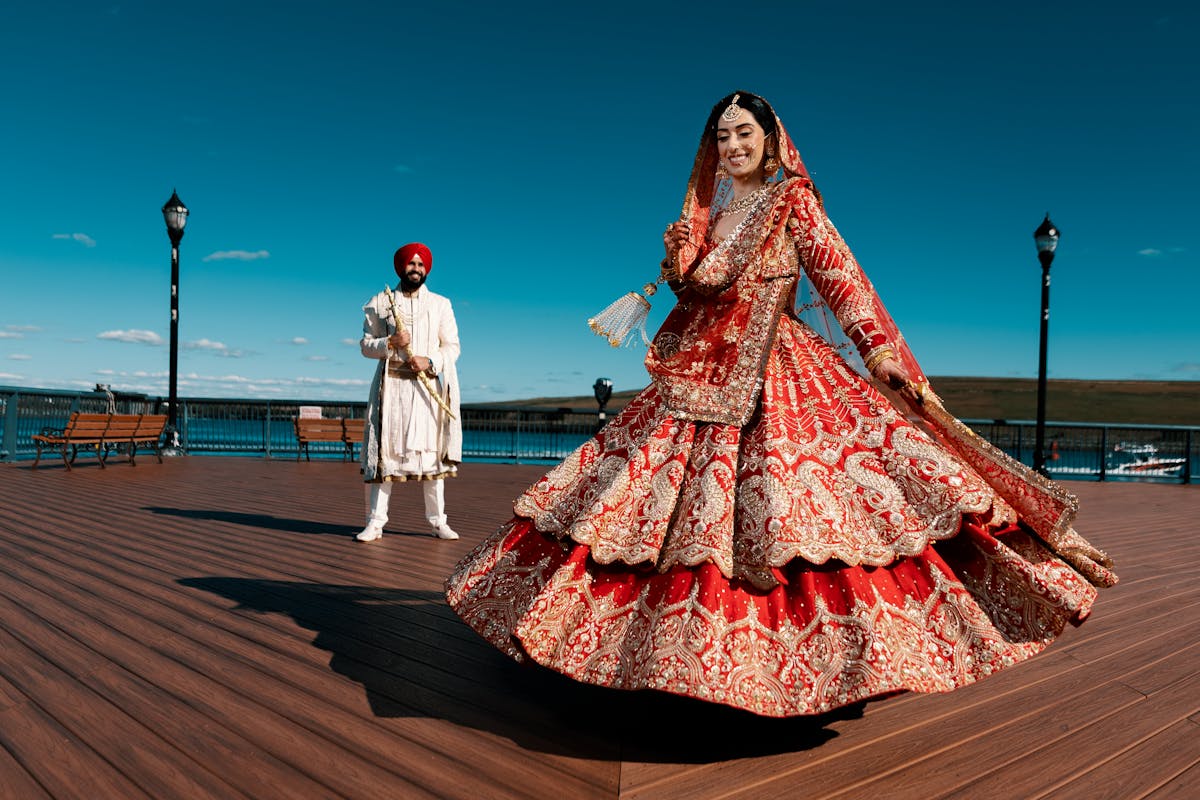Indian bride twirling red bridal lehenga at waterfront wedding — Panigrahana Weddings Bangalore
